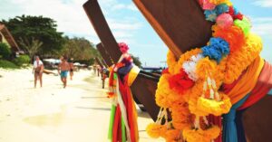 Vibrant longtail boats adorned with flowers on a sunny Thai beach.
