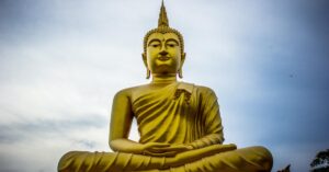 A majestic golden Buddha statue against a serene blue sky, symbolizing peace and spirituality.
