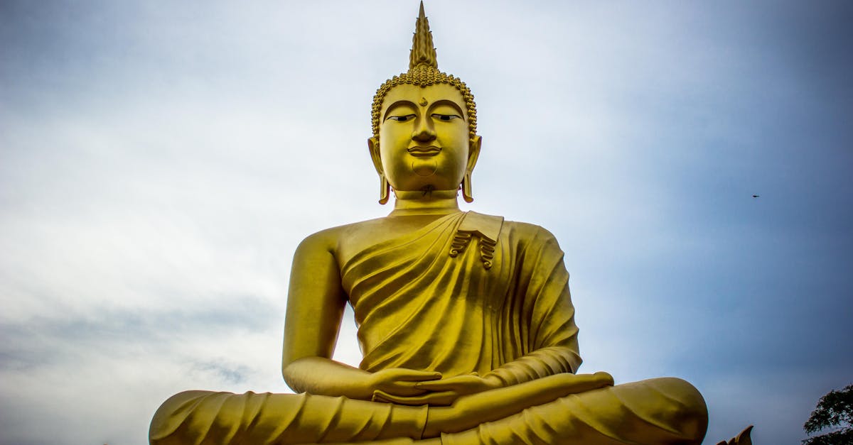 A majestic golden Buddha statue against a serene blue sky, symbolizing peace and spirituality.