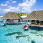 A scenic view of overwater bungalows and a couple enjoying a tropical paradise in the Maldives.