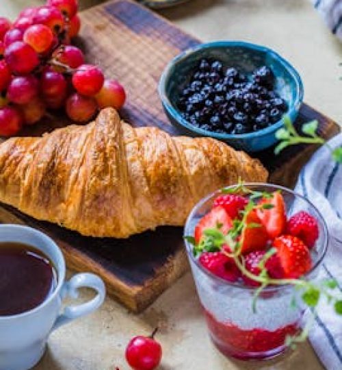 Vibrant breakfast setup featuring a croissant, fresh fruit, and coffee.