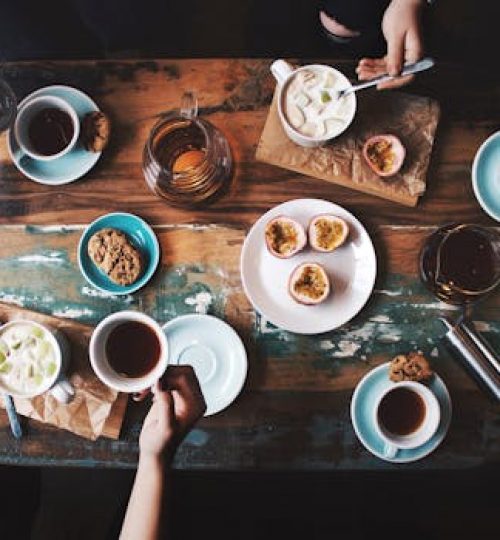Overhead view of a cozy coffee table setup with cups, snacks, and books, perfect for a relaxing afternoon.