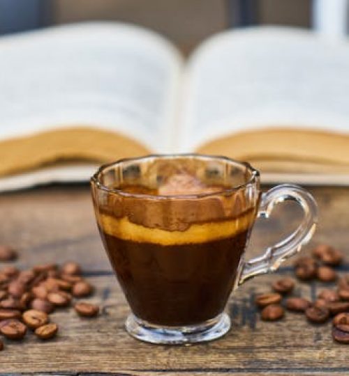 A rich espresso cup surrounded by beans and an open book, perfect for a relaxing break.